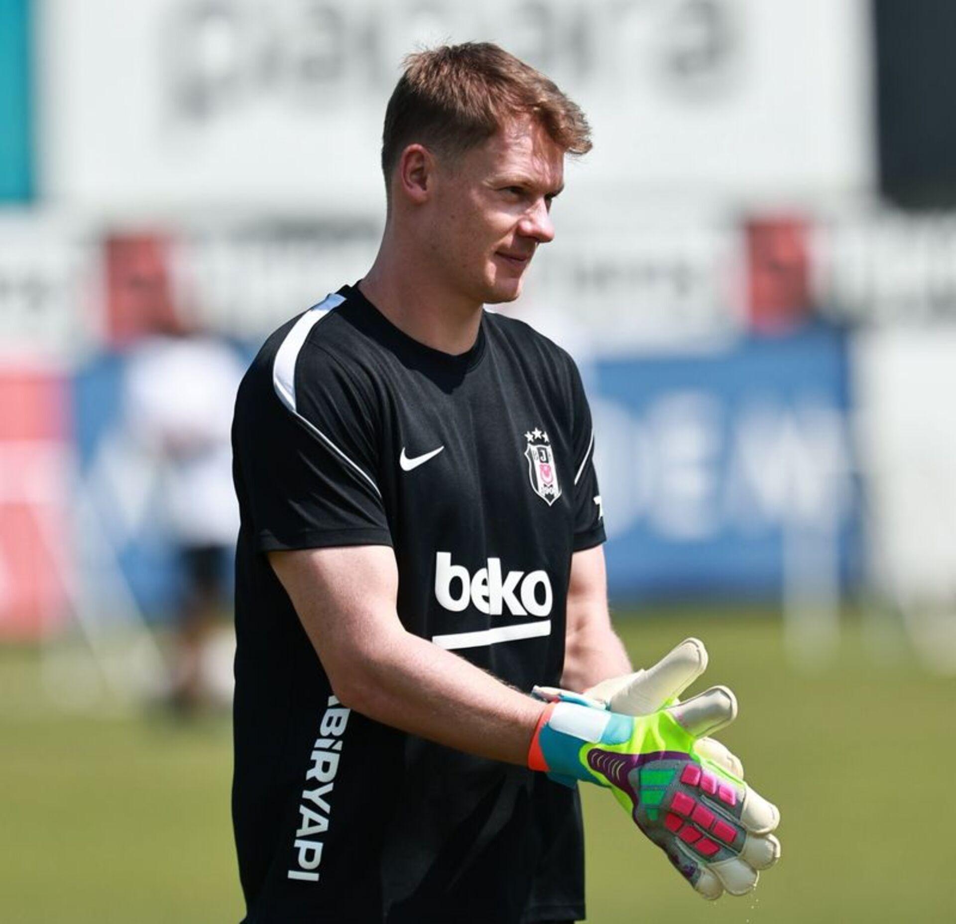 Alexander Nübel, Beşiktaş antrenman sahasında siyah antrenman formasıyla kaleci eldivenlerini takarken görülüyor.