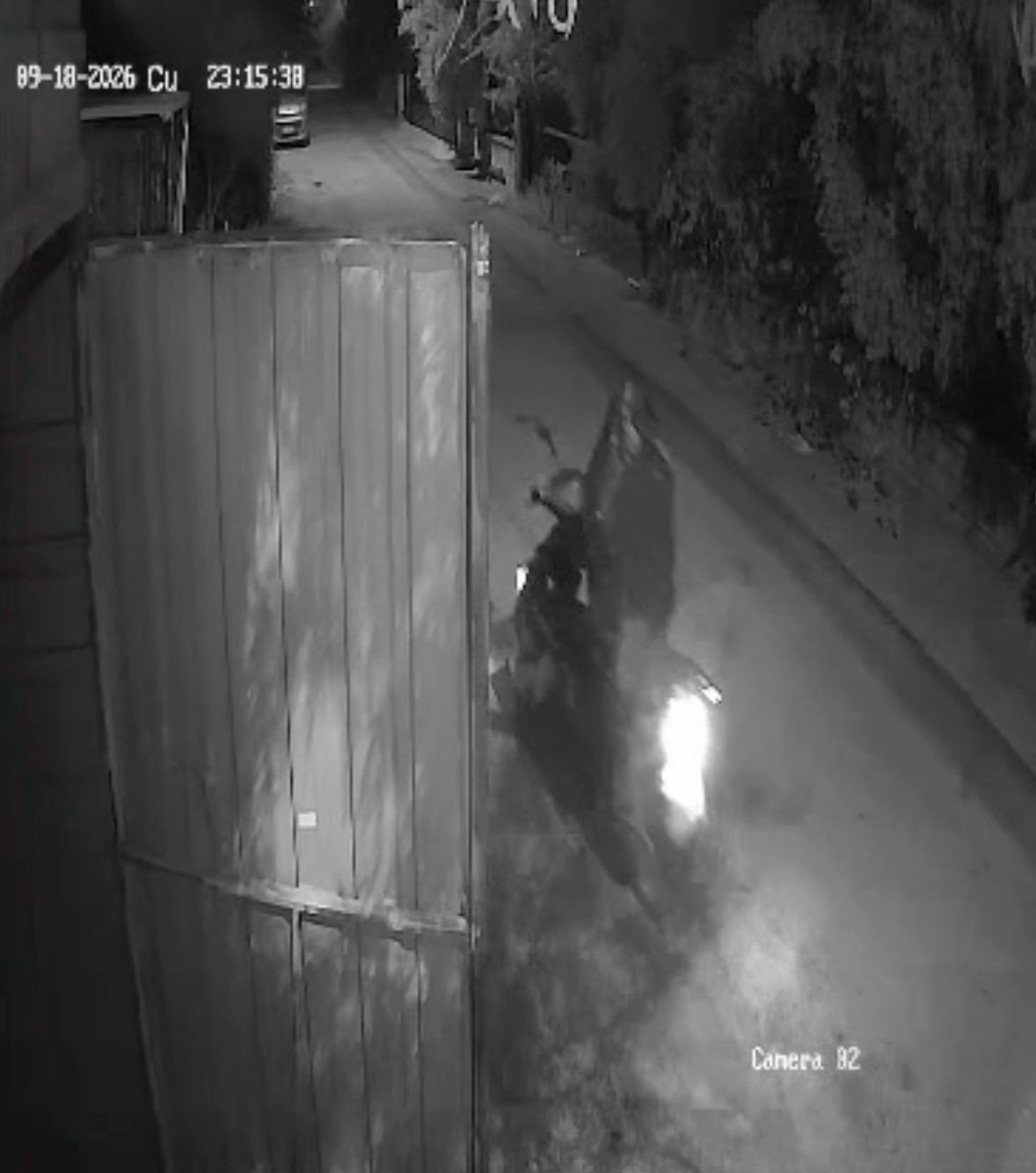 A suspect on a motorcycle is seen in front of the garage door on night-vision security footage.