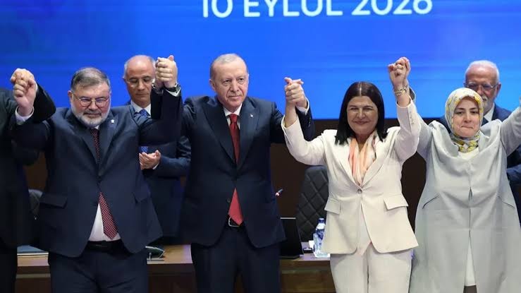 Cumhurbaşkanı Recep Tayyip Erdoğan’ın da bulunduğu bir toplantıda sahnede el ele poz veren siyasetçiler.