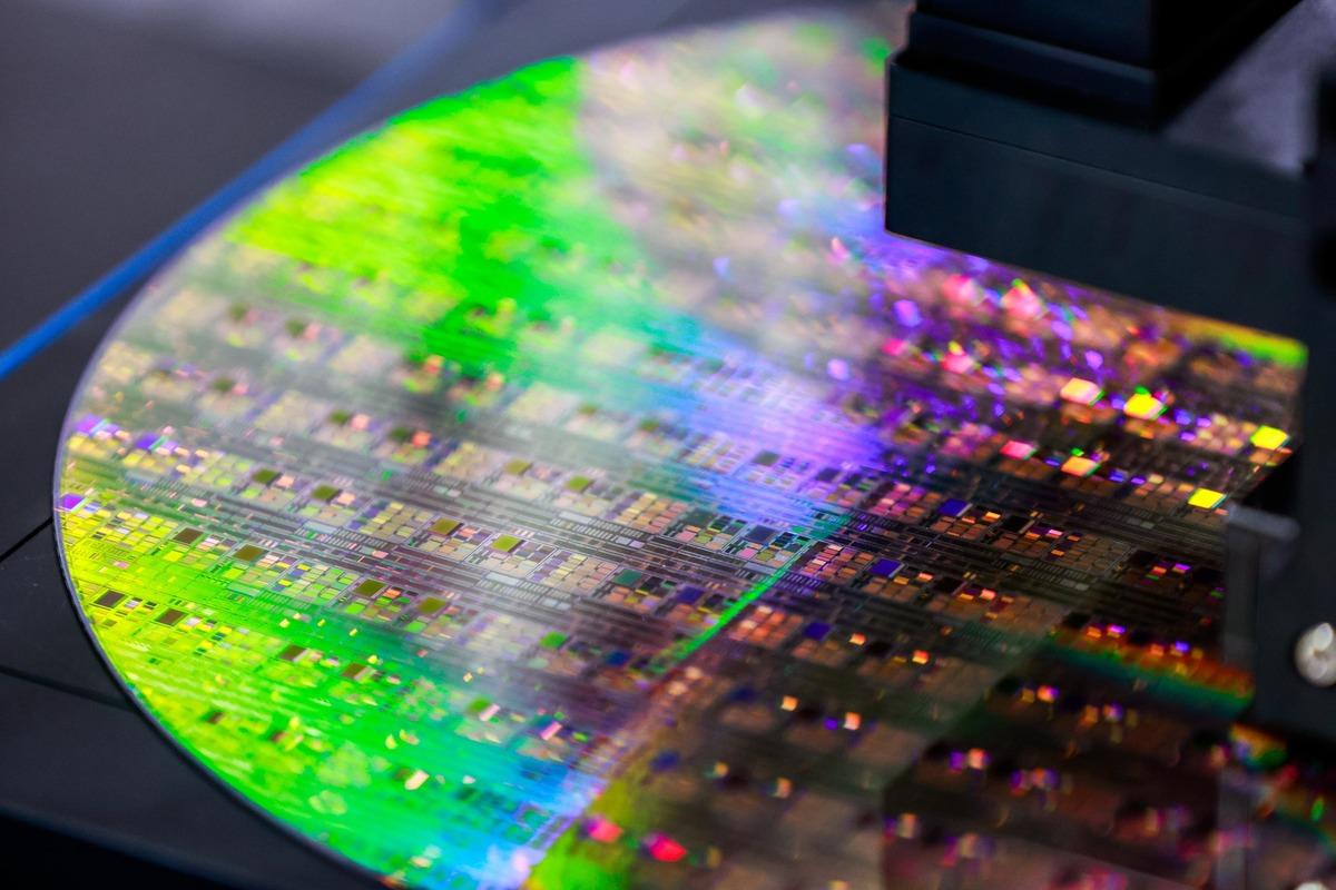 Renkli ışık yansımaları altında yarı iletken wafer yüzeyi ve üretim ekipmanının yakın plan görüntüsü.