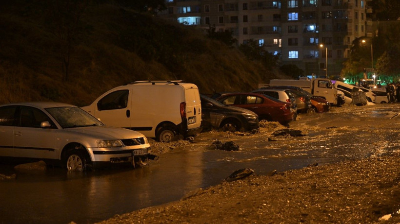 Gece saatlerinde su ve çamurla kaplanan yolda park halindeki araçlar görülüyor.