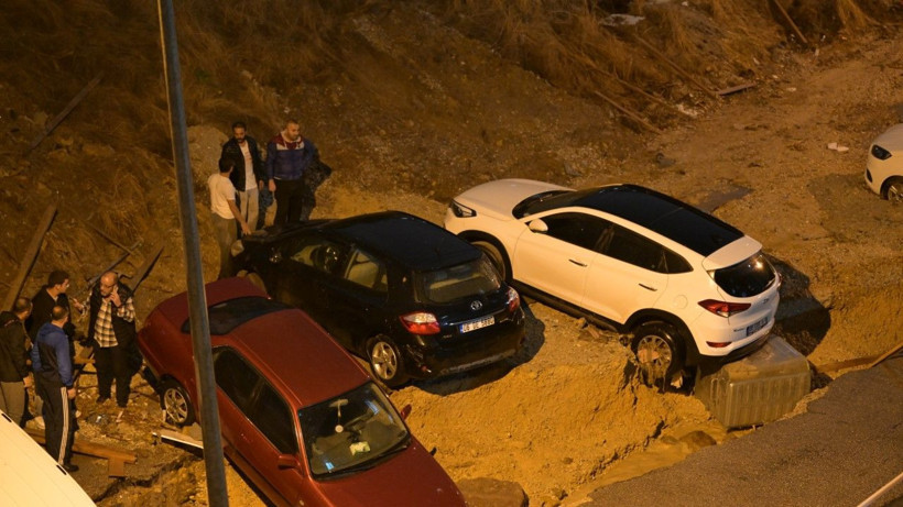 Çamurlu alanda farklı yönlere savrulmuş araçlar görülüyor.