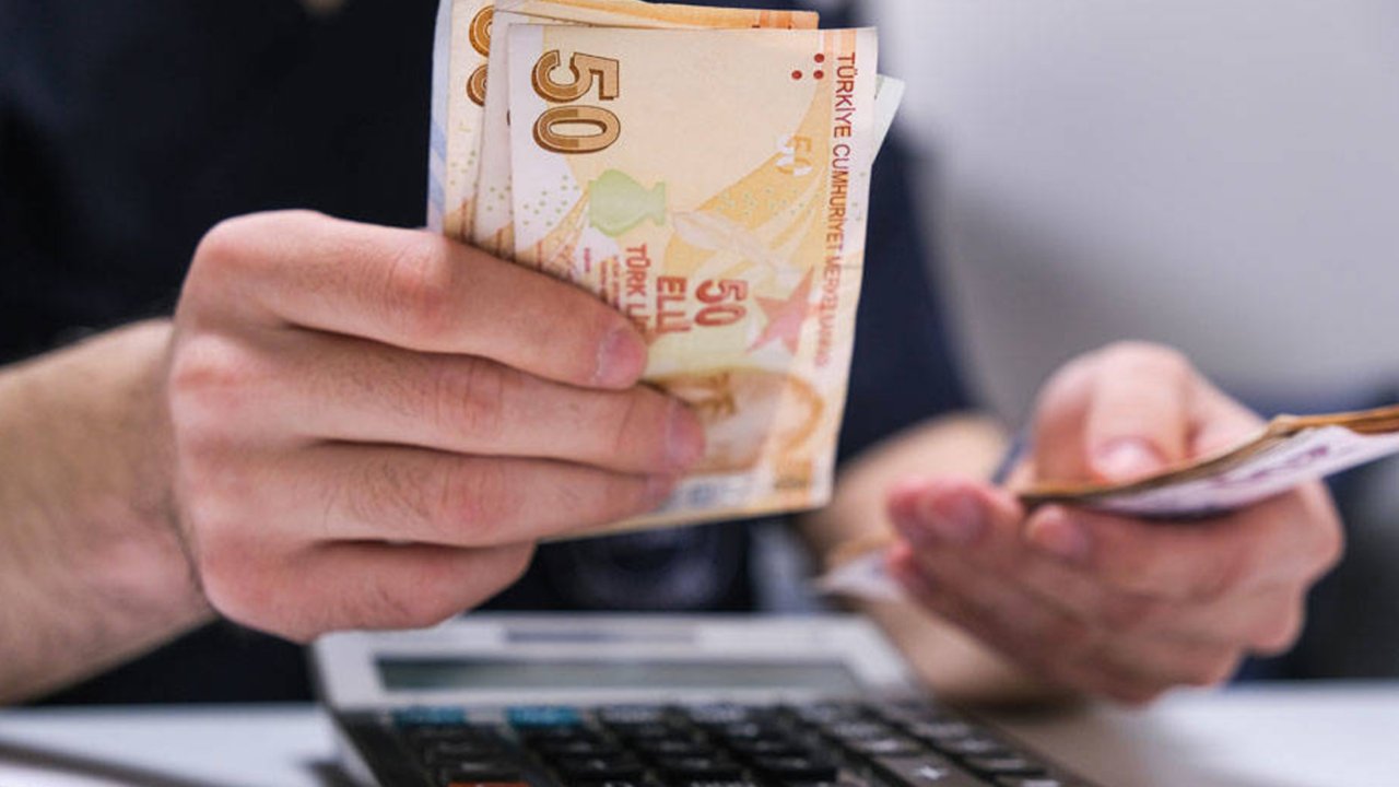 Elde Türk lirası banknotları ve masada hesap makinesi.