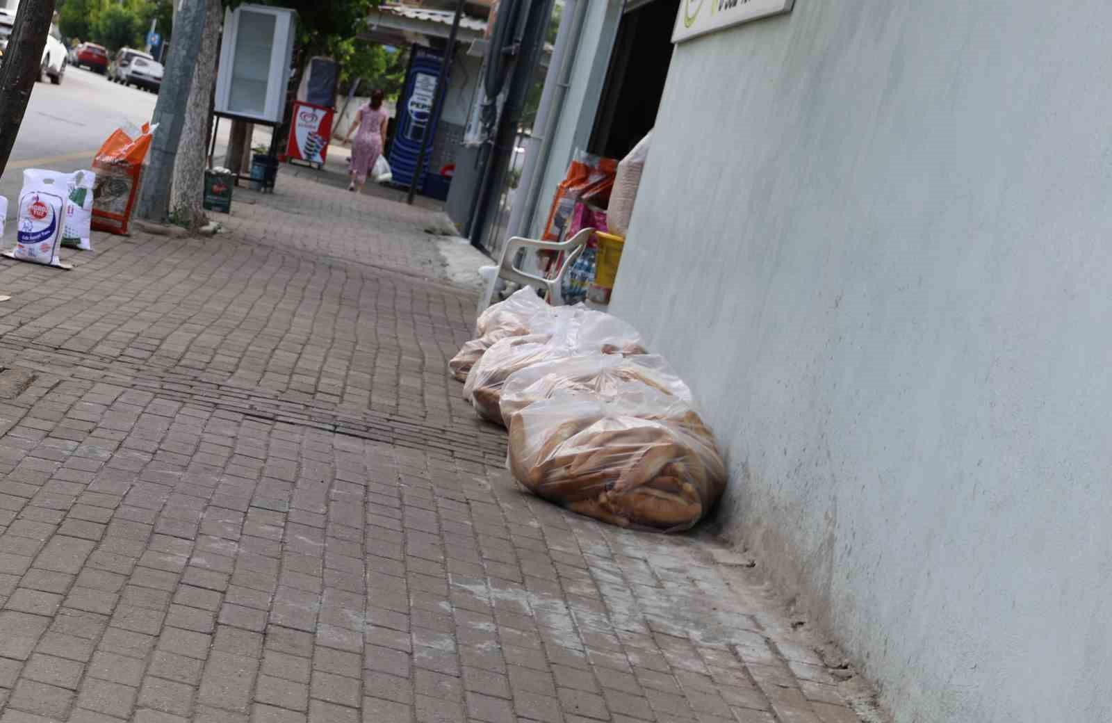Stale bread collected in bags on the sidewalk in front of a business.
