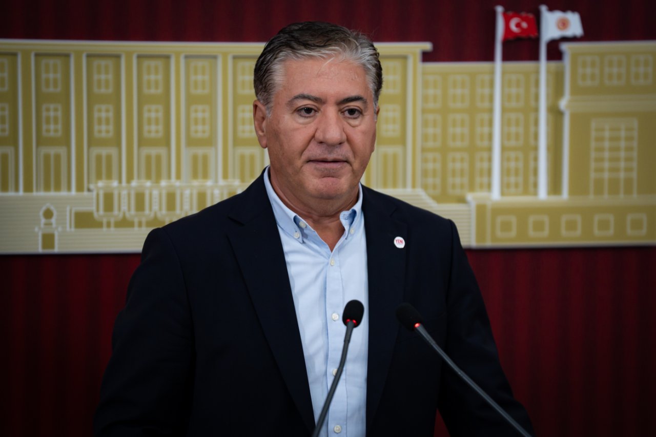 Murat Emir’in Meclis arka planı önünde mikrofonlarla konuştuğu yakın plan görüntü.