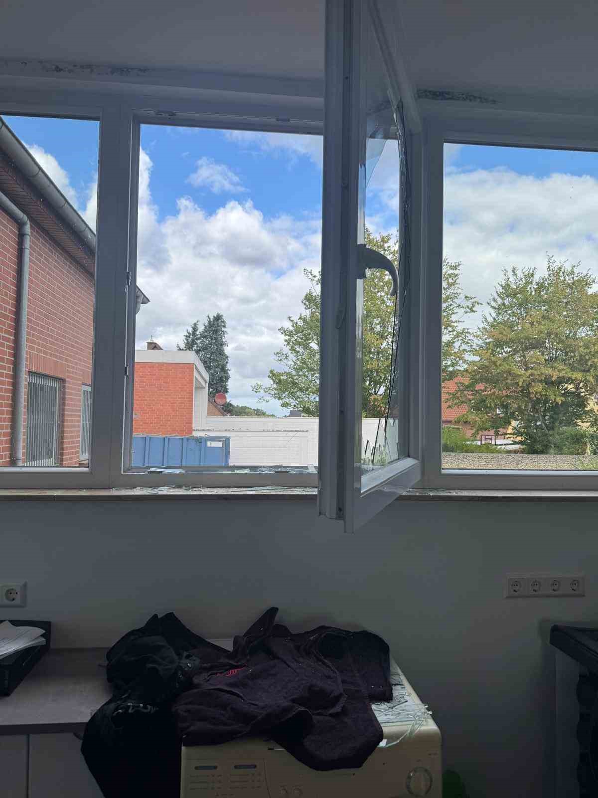Açık pencere, kırık cam parçaları ve iç mekânda dağılmış eşyalar.