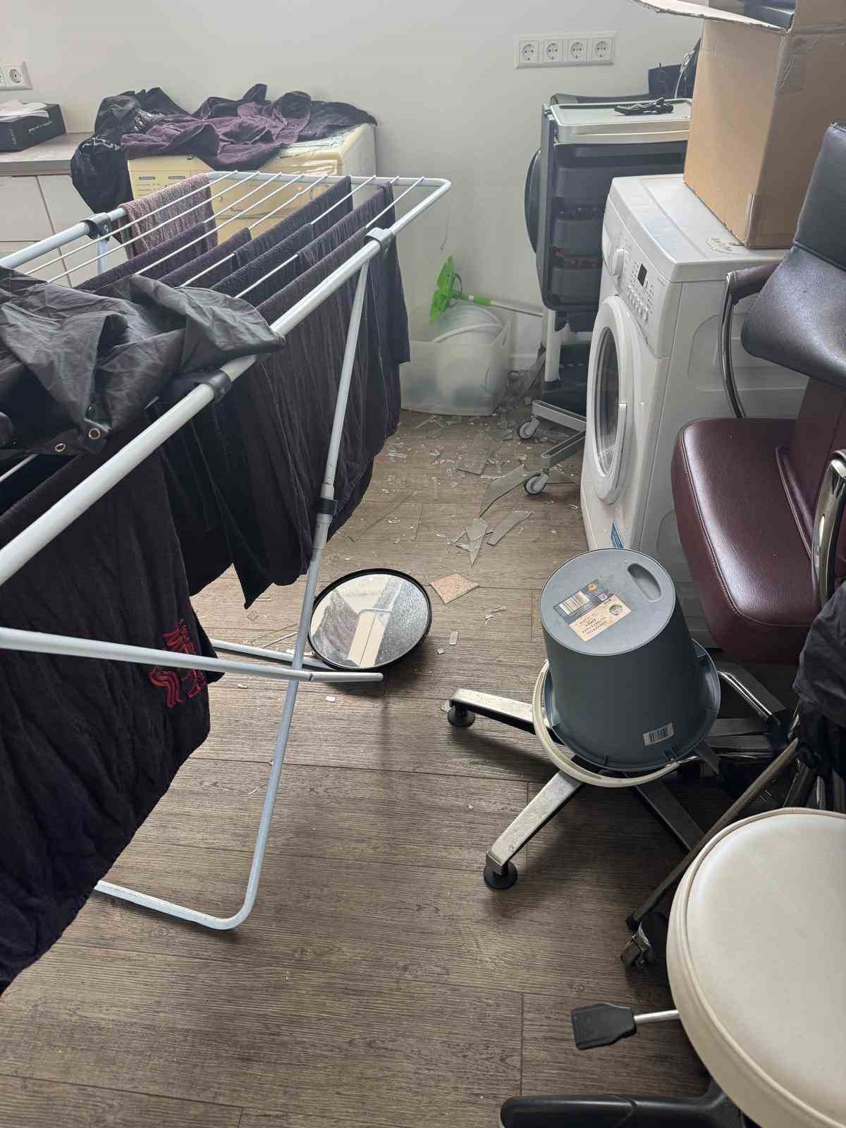 Kuaför salonunda yerde cam kırıkları, kurutma askısı, koltuk ve çeşitli ekipmanlar.