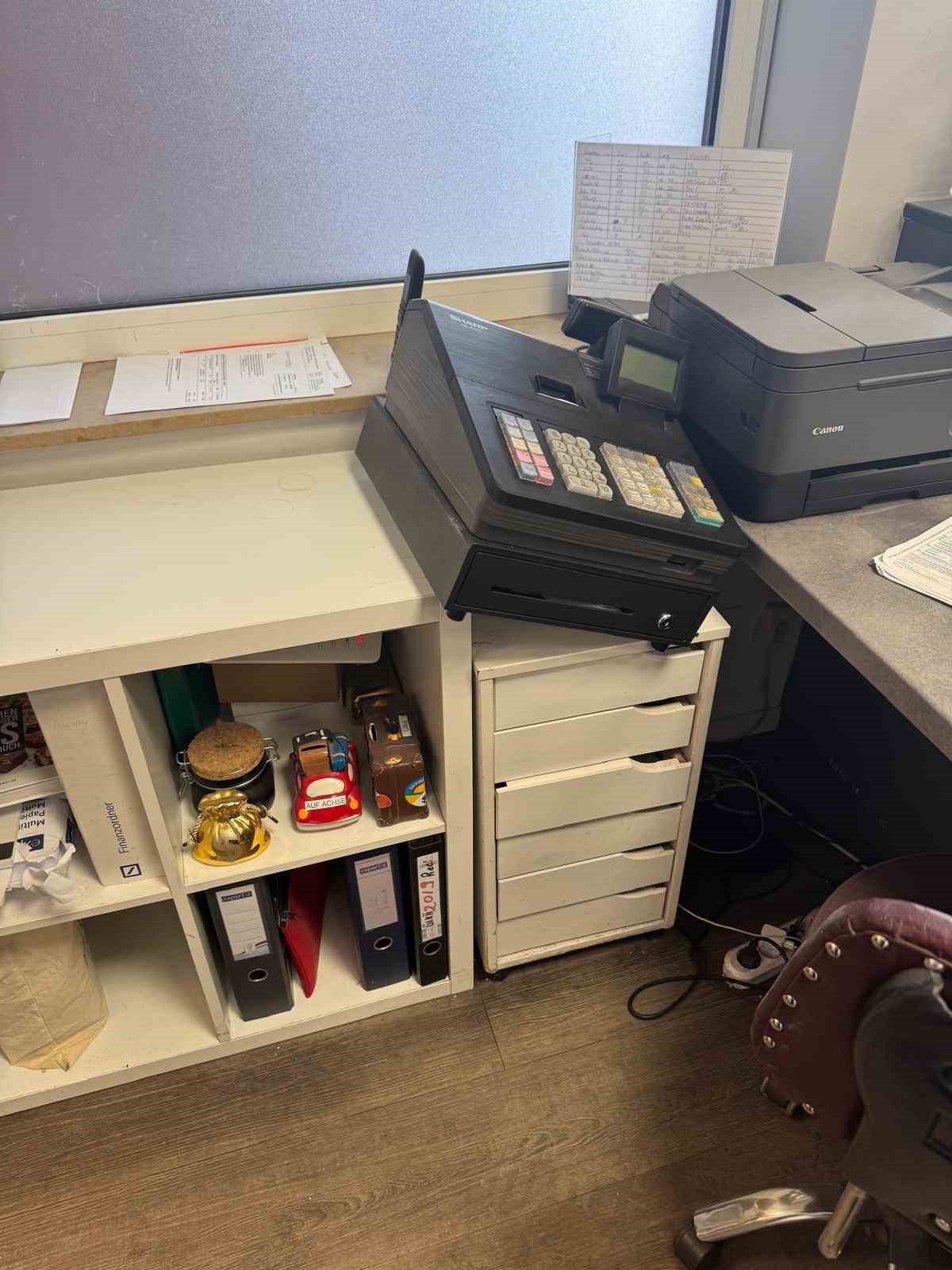 Kuaför salonunda kasa, yazıcı, evraklar ve ofis malzemelerinin bulunduğu bölüm.