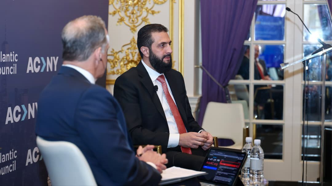 Syrian President Ahmed al-Sharaa is seen with the session moderator at the Atlantic Council panel.