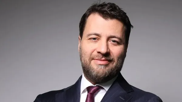 Emre Tezmen’in gri arka plan önünde çekilmiş portre fotoğrafı.