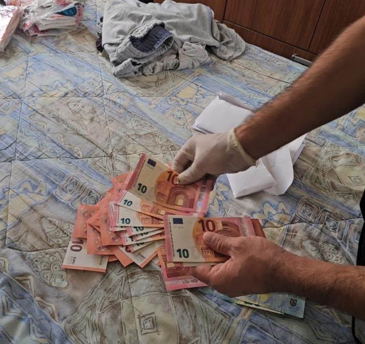 An image of an official counting euro banknotes on a bed.
