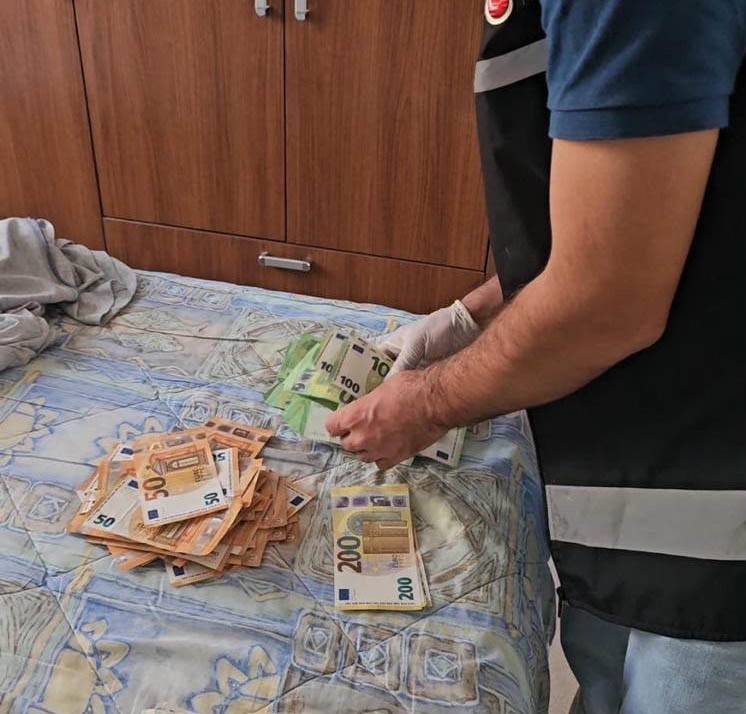 Stacks of euro banknotes on a bed and the examination by personnel.