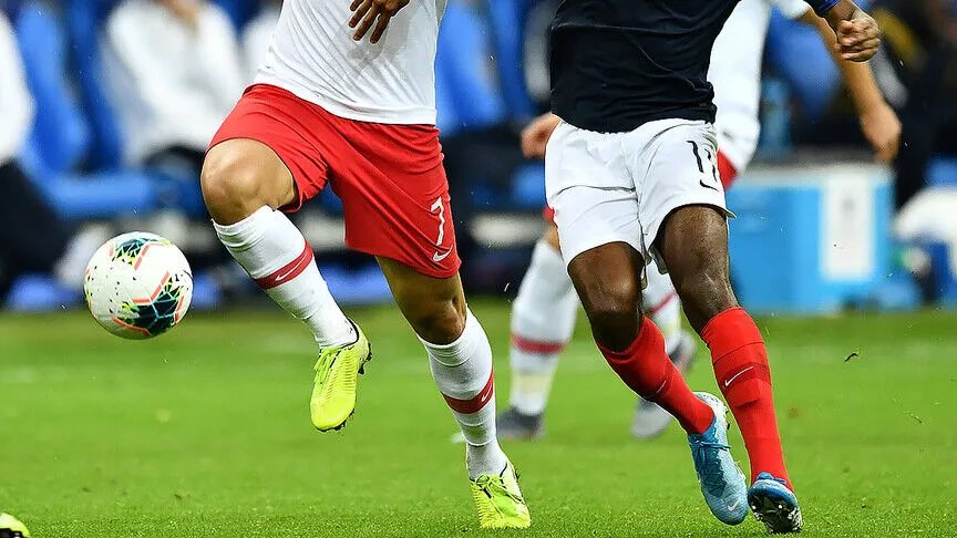 Futbol sahasında Türkiye ve Fransa formalarını temsil eden oyuncuların mücadele anı.