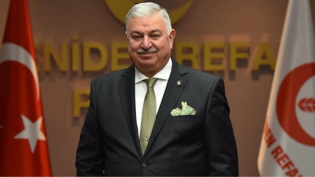 Doğan Bekin, Yeniden Refah Partisi arka planı önünde görülüyor.