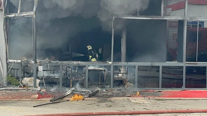 A firefighter is seen intervening at the restaurant where the fire broke out, with heavy smoke visible inside.