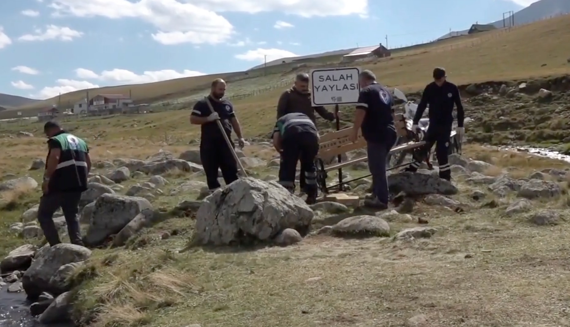 Trabzon’daki yaylada “Salah Yaylası” tabelası ve bankın bulunduğu alanda çalışan ekipler.