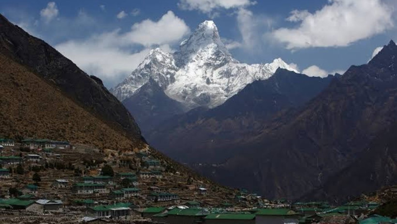 A snow-covered peak in the Himalayas and residential areas in the valley.