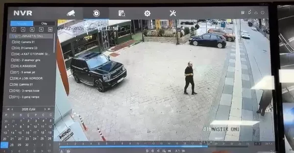 İşyeri önündeki açık alanda kişilerin ve park halindeki araçların görüldüğü güvenlik kamerası karesi.