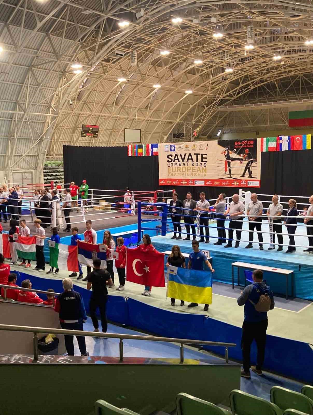 Savate Combat Avrupa Şampiyonası salonunda farklı ülkelerden sporcular ve ring alanı görülüyor.