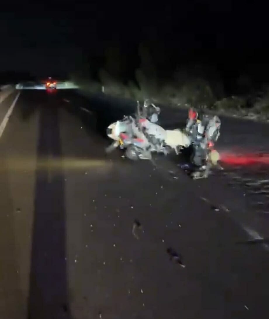 Gece vakti kara yolunda hasar gören motosiklet ve çevreye saçılan parçalar.