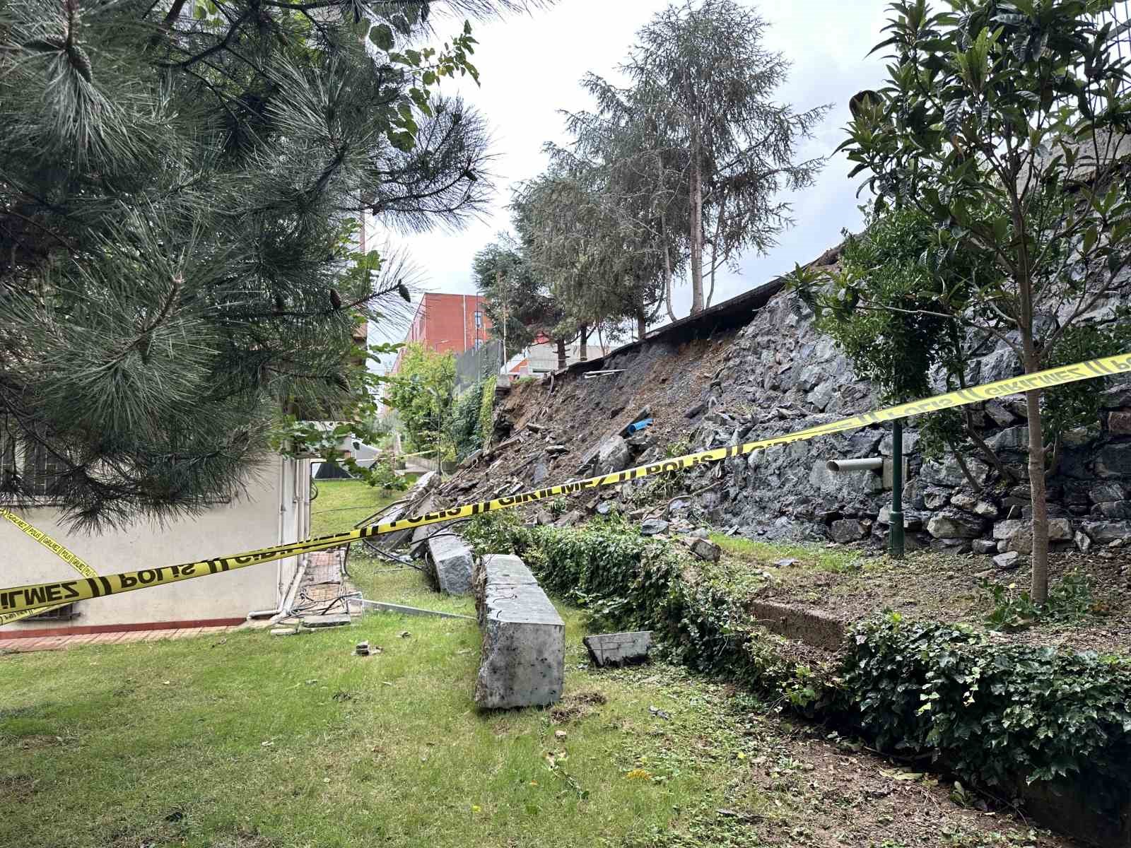 Jardín acordonado con cinta de seguridad y escombros en la zona del muro derrumbado.