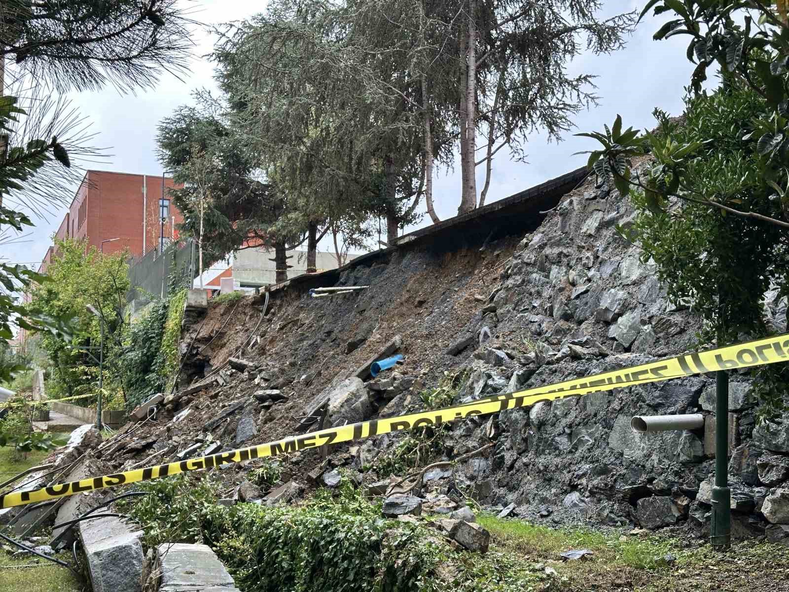 Sección derrumbada del muro de contención, escombros en la ladera y cinta de seguridad.