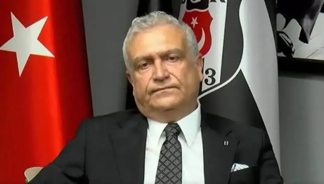 Hakan Daltaban est vu en costume devant un fond arborant le drapeau turc et l'emblème de Beşiktaş.