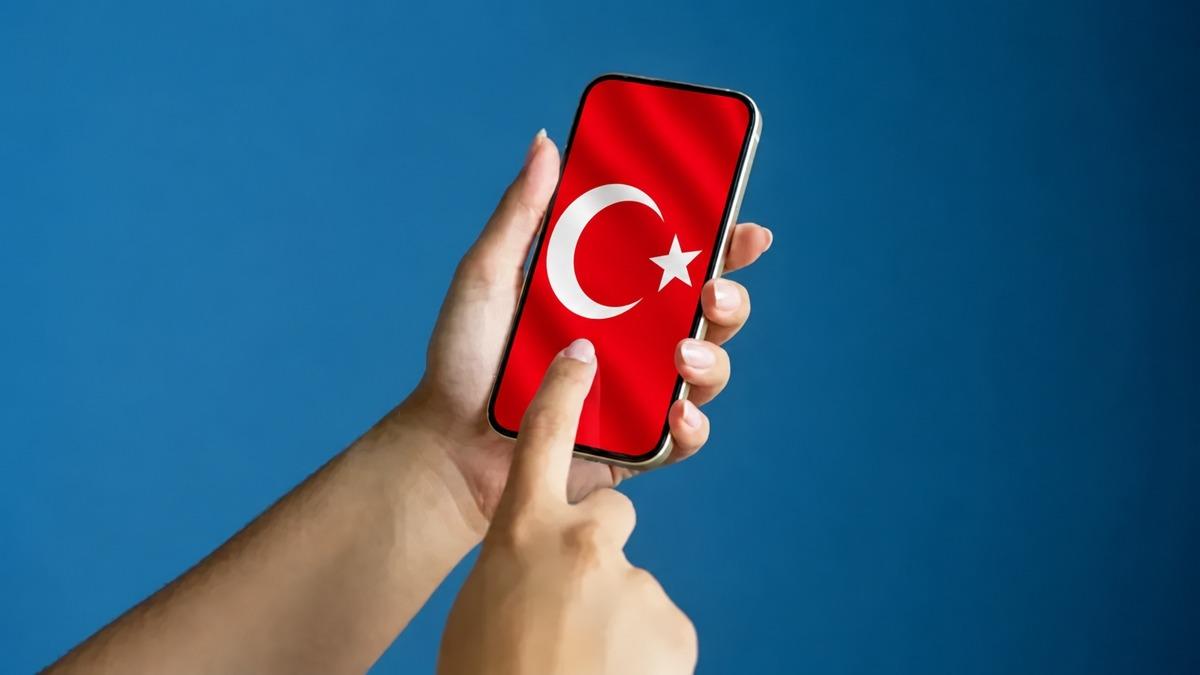 Des mains tenant un smartphone sur lequel apparaît le drapeau turc.