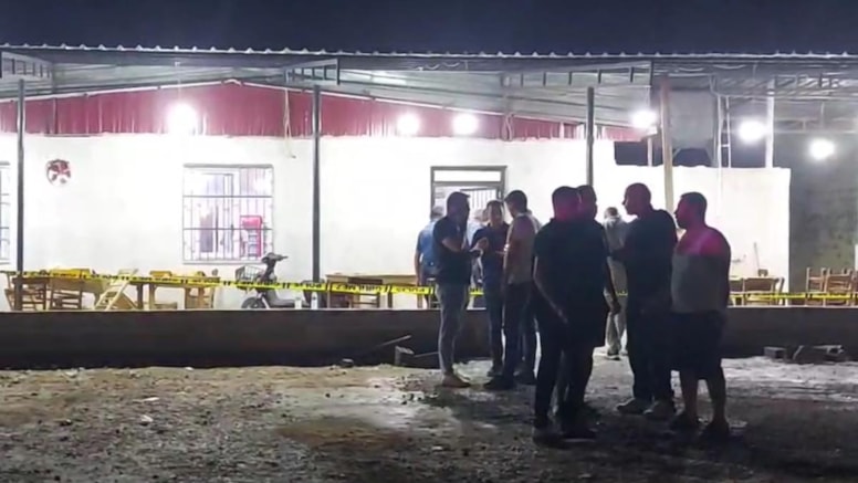 Gece saatlerinde polis şeridiyle çevrilen kahvehane çevresinde bekleyen kişiler.