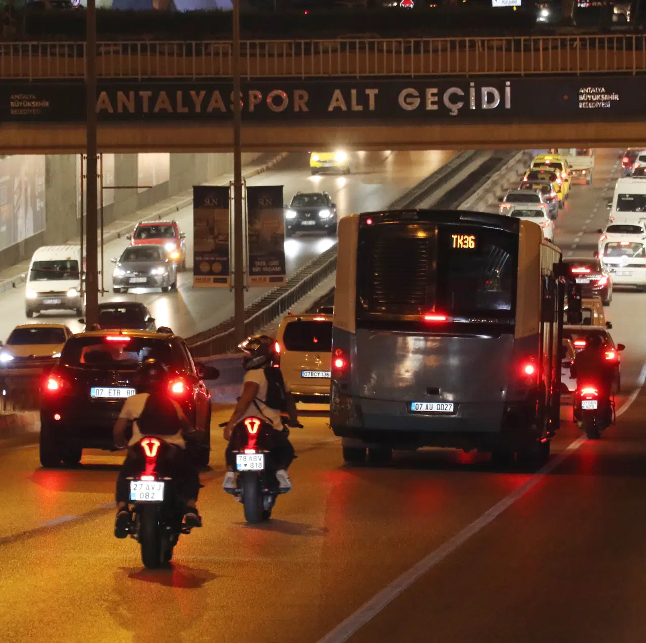 Gece saatlerinde yoğun trafikte ilerleyen motosikletler, otomobiller ve otobüs.