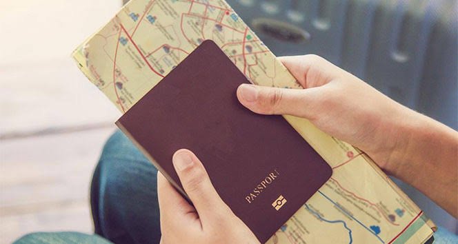 An image showing a person preparing for travel while holding a passport and a map.