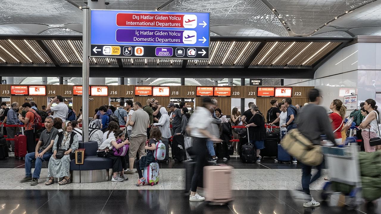 Passengers and their luggage waiting in the international departures section of the airport.