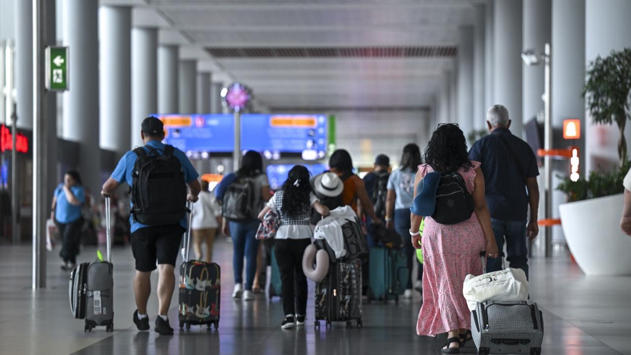 Passengers walking with their luggage in the airport terminal.