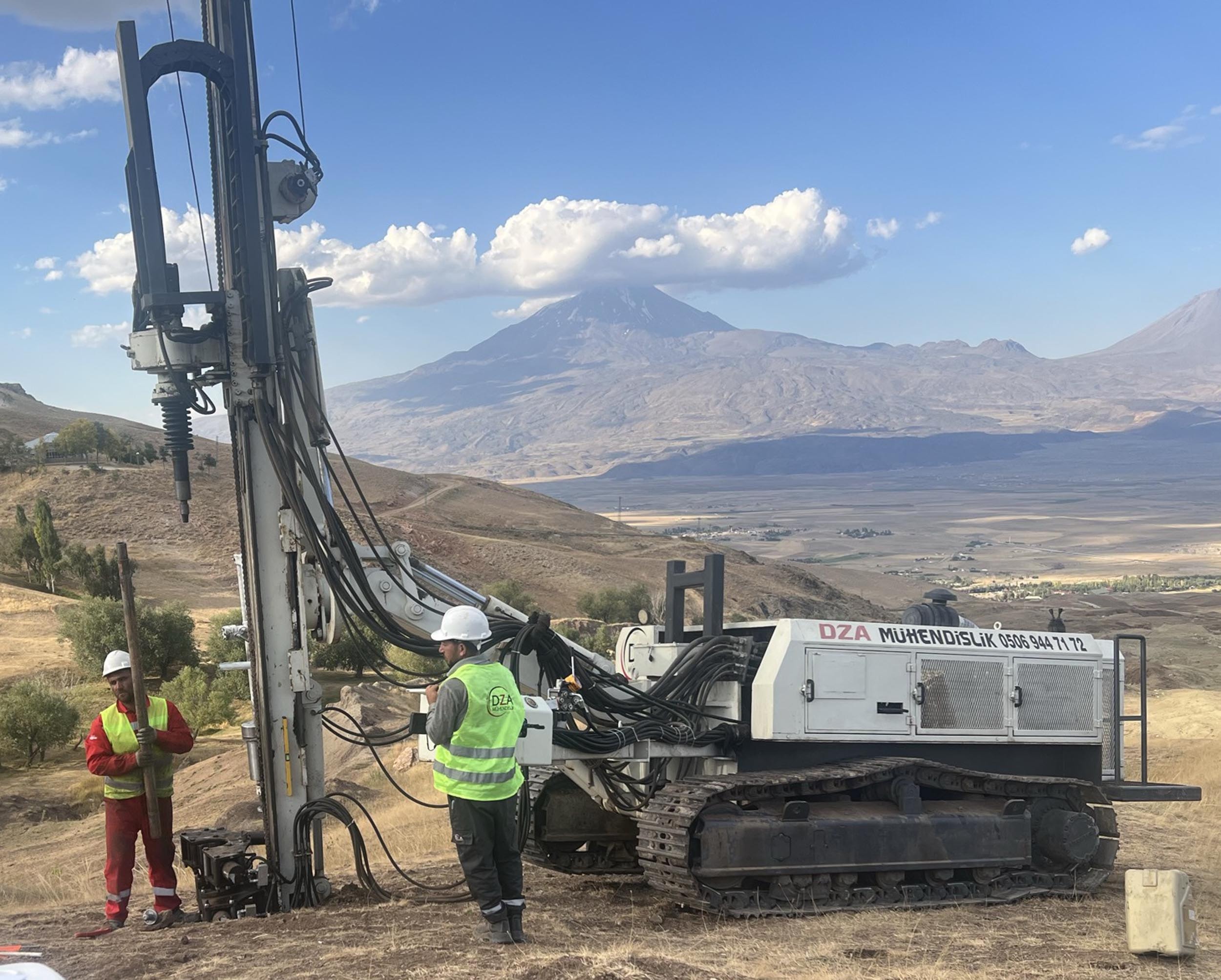 Teammitglieder bei der Arbeit mit der Bohrmaschine vor der Kulisse des Berges Ararat.
