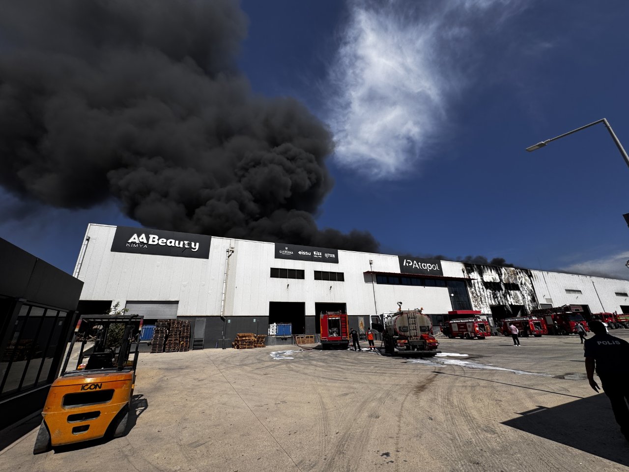 Mersin’de yangın çıkan fabrika binasından yükselen siyah duman ve olay yerindeki itfaiye araçları.