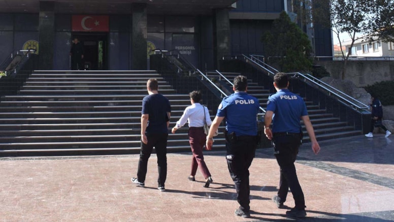 Buca Belediyesi binası girişine doğru yürüyen polisler ve beraberindeki kişiler.