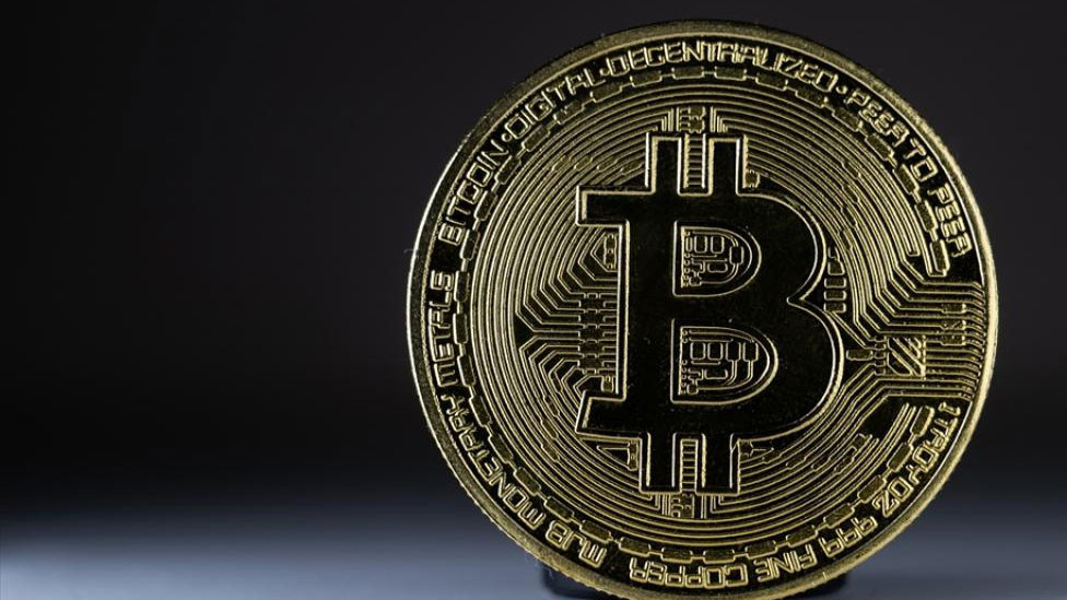 Koyu arka plan önünde Bitcoin temsili madeni para görseli.