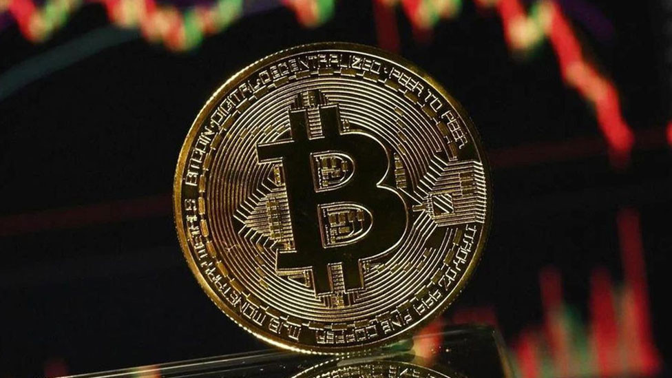 Grafik ekranı önünde Bitcoin temsili madeni para görseli.