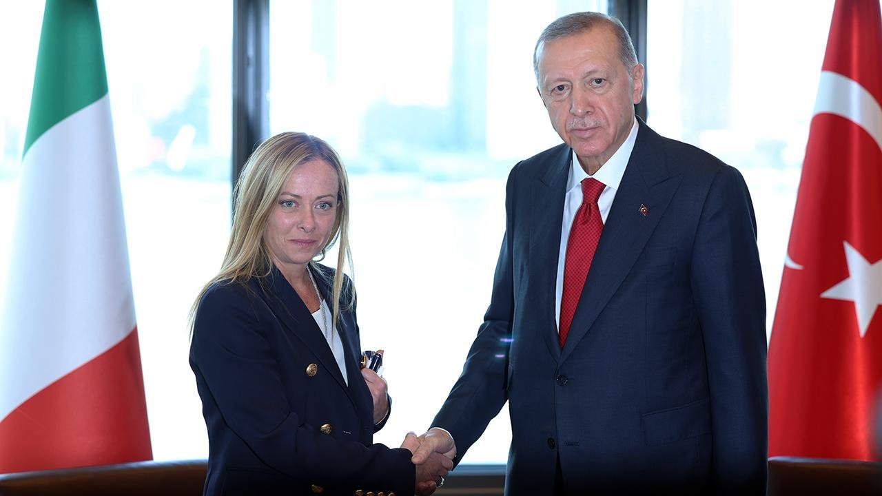 Giorgia Meloni ile Recep Tayyip Erdoğan’ın Türkiye ve İtalya bayrakları önünde tokalaştığı görüntü.