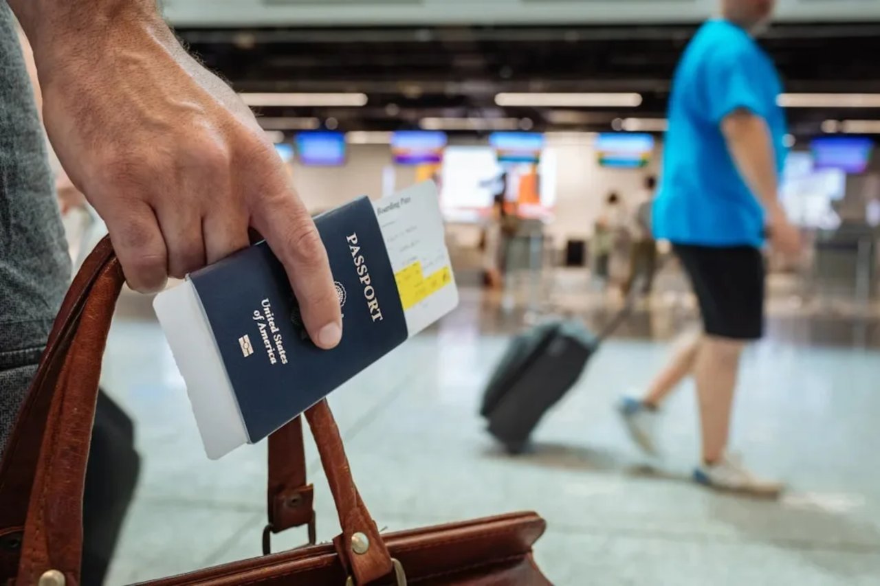 Havalimanında pasaport ve bilet tutan bir yolcu.