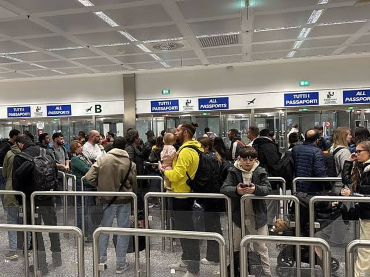 Havalimanında pasaport kontrol noktası önünde bekleyen yolcu kalabalığı.
