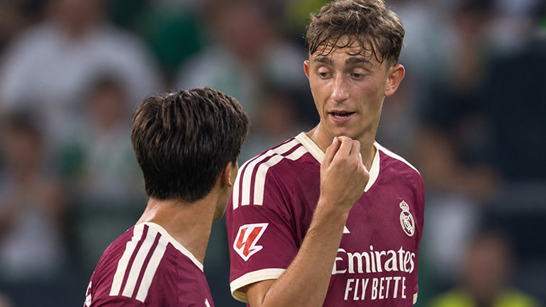 Real Madrid players Arda Güler and Dean Huijsen are seen talking on the pitch.