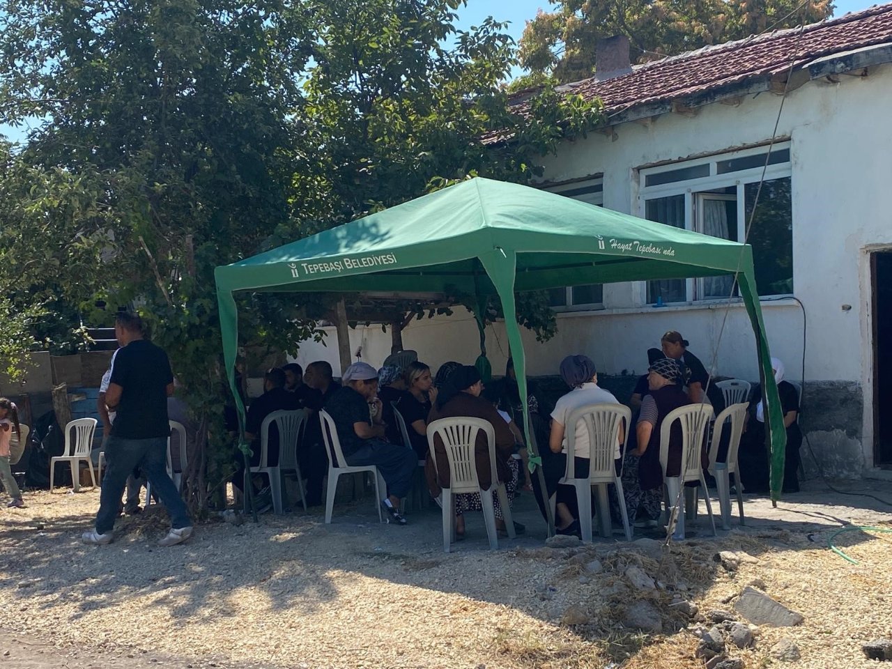 Tepebaşı Belediyesi yazılı yeşil taziye çadırı altında oturan kişiler görülüyor.