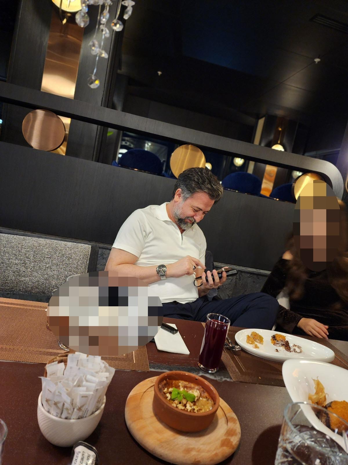 Photo of a person looking at their phone at a restaurant table.