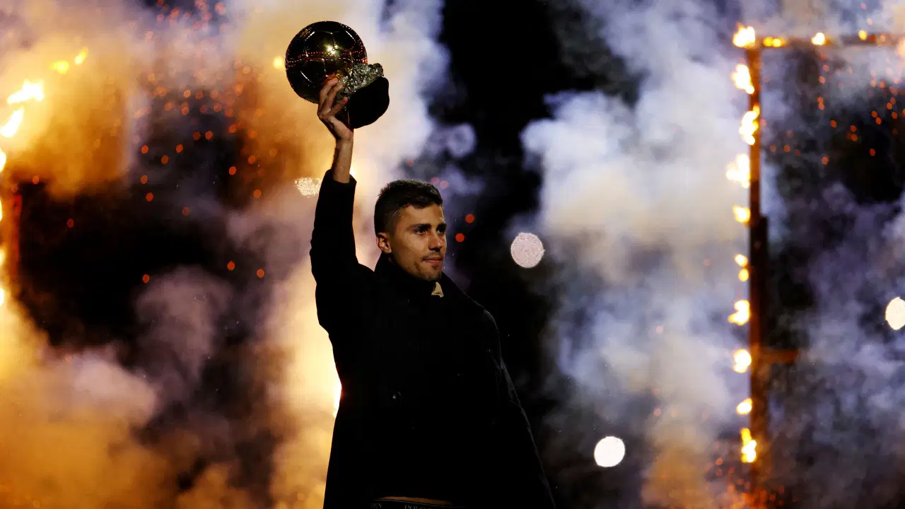 A footballer lifting the Ballon d'Or trophy is seen in the ceremony atmosphere.
