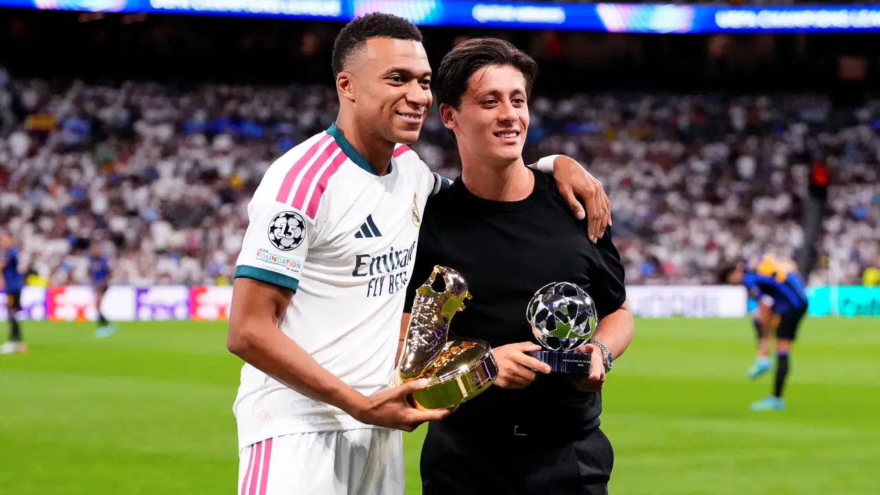 Arda Güler ile Kylian Mbappe, Şampiyonlar Ligi ödülleriyle sahada yan yana duruyor.